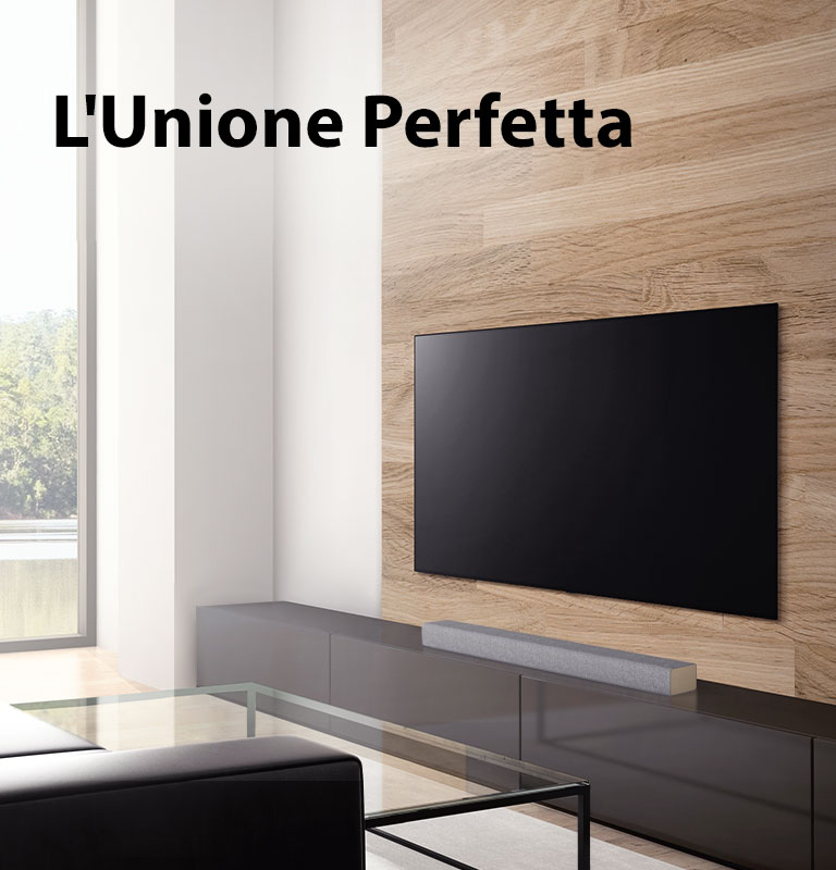 Una soundbar è poggiata su un mobiletto TV bianco e un TV è appeso a una parete in legno. La visuale fuori dalla finestra è su un bosco. Testo sopra l’immagine: The Best Match with LG TVs (l’abbinamento perfetto per i televisori LG).