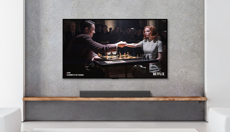 Una soundbar e un TV in un salotto bianco Una donna e un uomo stanno giocando a scacchi sullo schermo del TV.