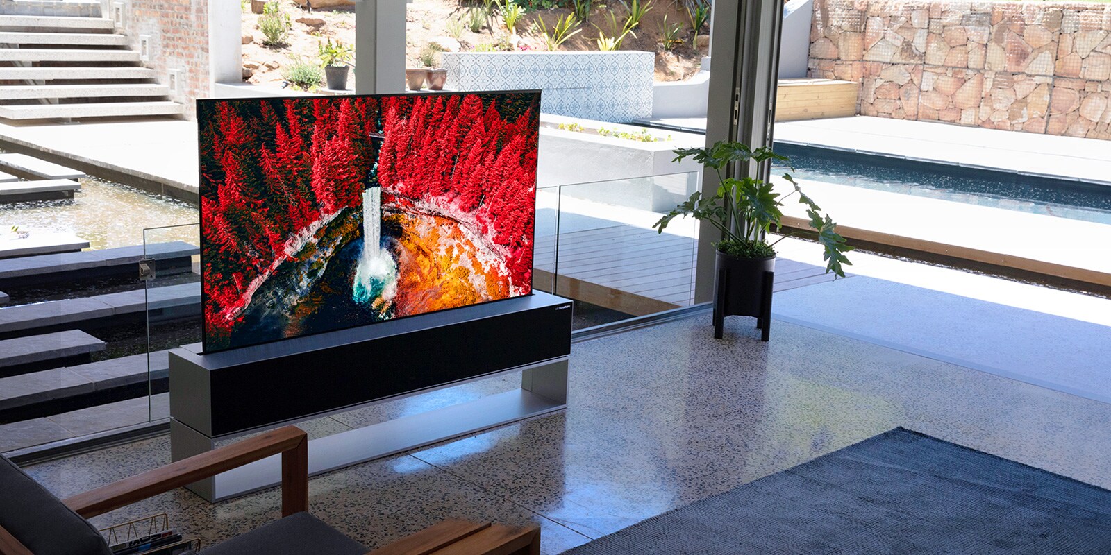 Un soggiorno di lusso con l'LG SIGNATURE Rollable OLED TV che visualizza una ripresa della natura dall'alto.