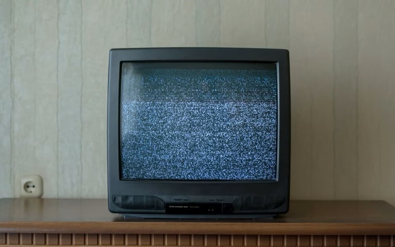 Un televisore vintage che mostra la statica, posto su un mobile di legno in una stanza a tema retrò.