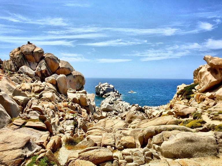 Vista aerea delle barche sulle acque limpide della costa della Sardegna, ideale per una vacanza con accessori da campeggio.