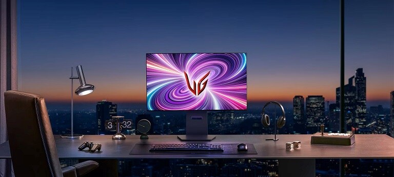 Una postazione gaming elegante con un monitor LG UltraGear illuminato da luci colorate, affacciata su un panorama urbano al tramonto attraverso una grande finestra.