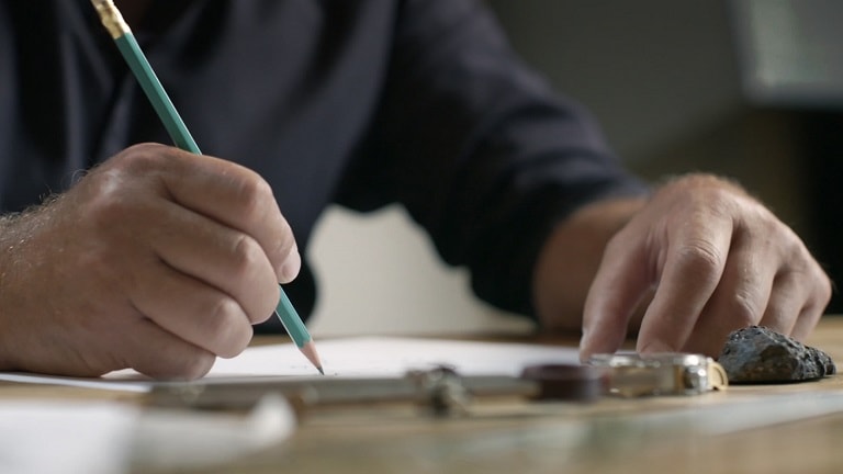  Primo piano di una persona che scrive con una matita a una scrivania.