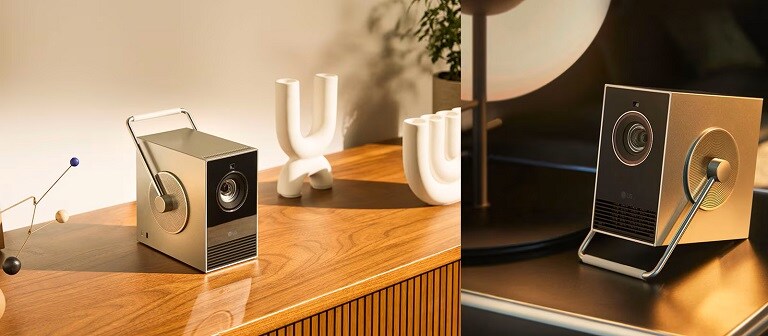 Due inquadrature ravvicinate di un elegante proiettore portatile su un tavolo di legno, circondato da decorazioni moderne con un’illuminazione soffusa.