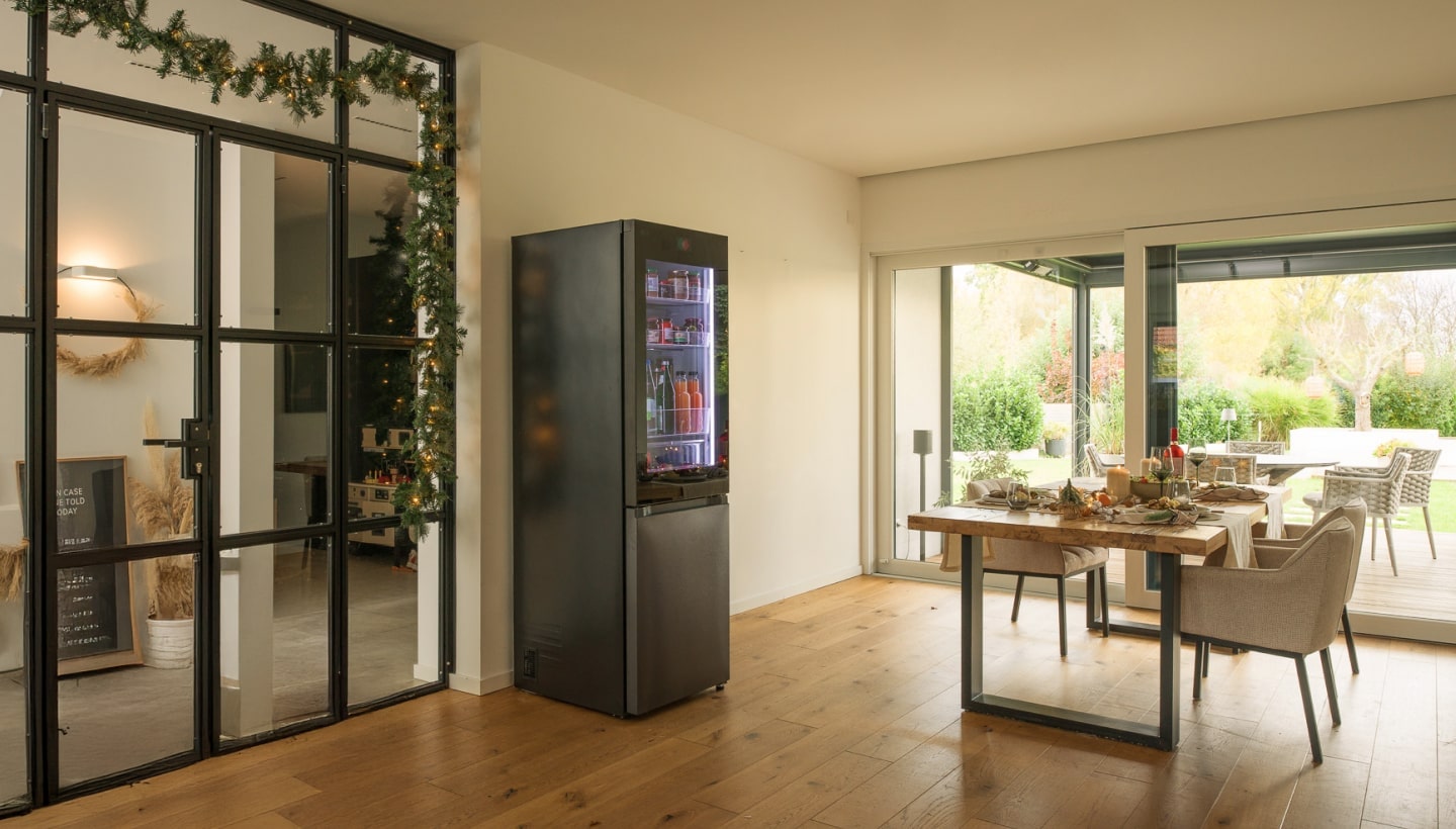 Una sala da pranzo moderna con LG InstaView, tavola festiva apparecchiata e vista su un giardino esterno.