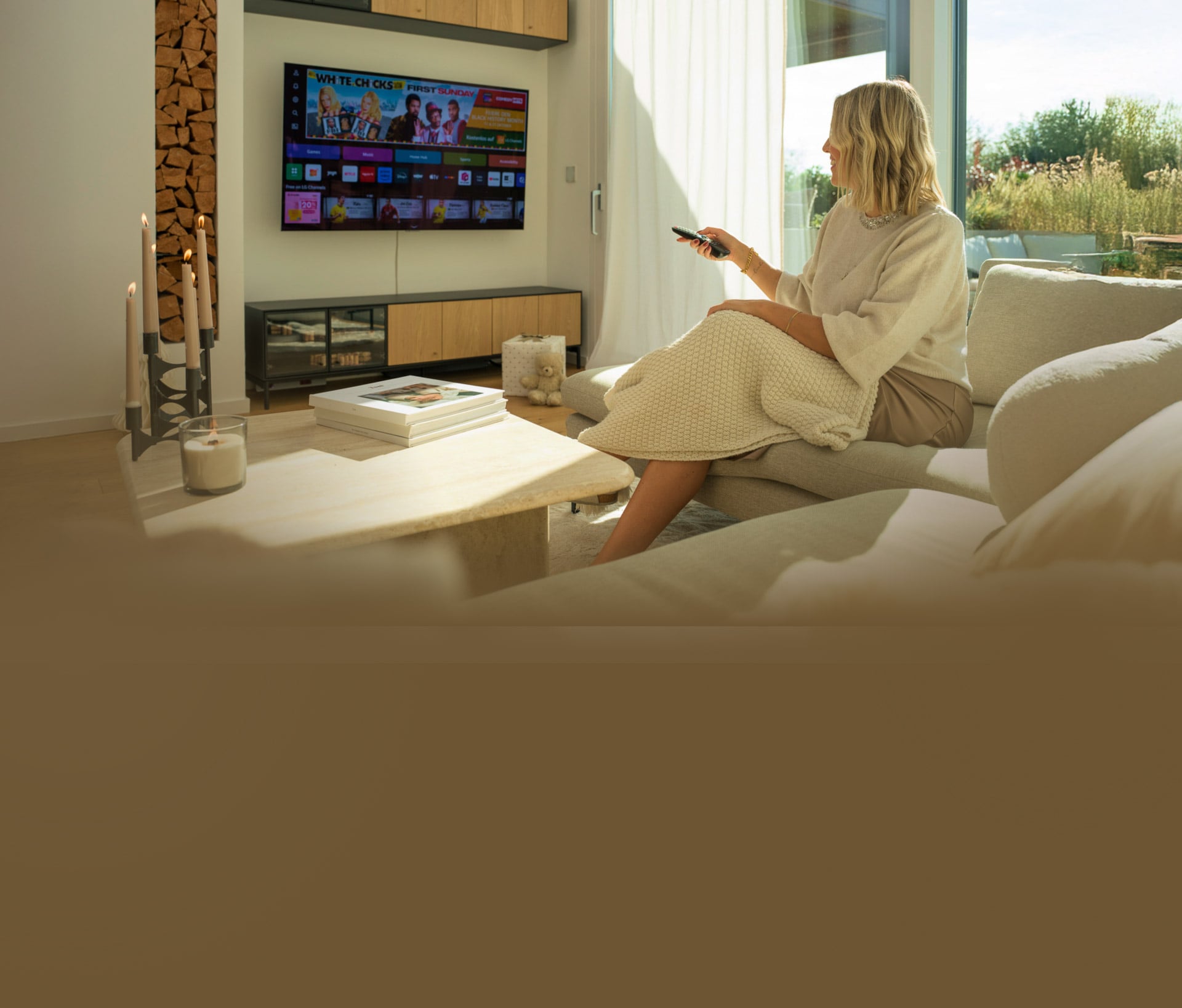 Una donna si rilassa sul divano in un soggiorno moderno, usando un telecomando per controllare la TV LG OLED G4 4K Smart.