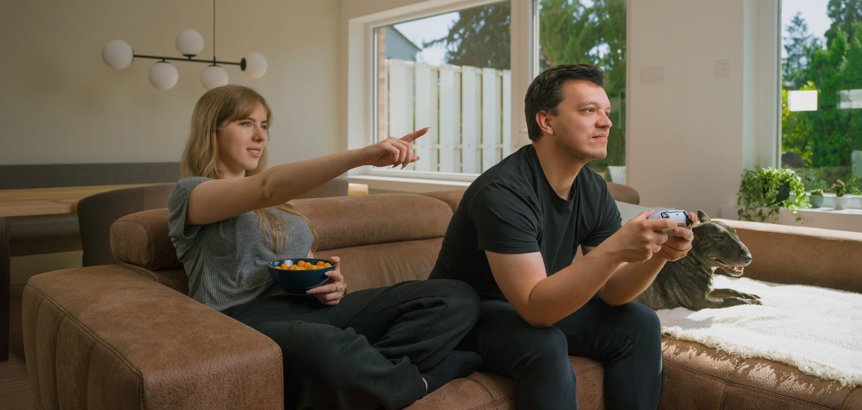 Coppia che si diverte giocando insieme in un soggiorno luminoso con una TV LG OLED, creando momenti di svago e relax condivisi.