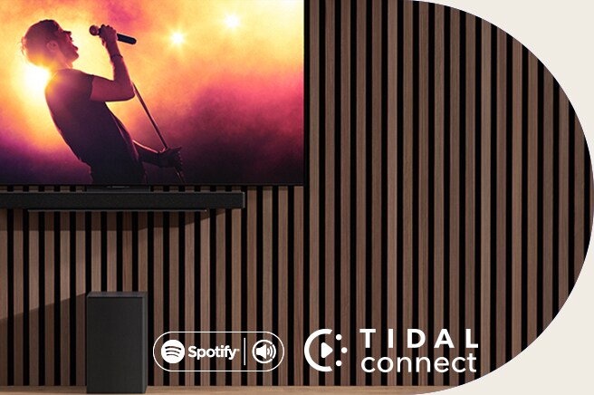 La LG OLED C è posizionata sulla parete, mentre la LG Soundbar SC9S è posizionata al di sotto tramite una staffa esclusiva. Il Subwoofer è posizionato sotto. La TV mostra la scena di un concerto.