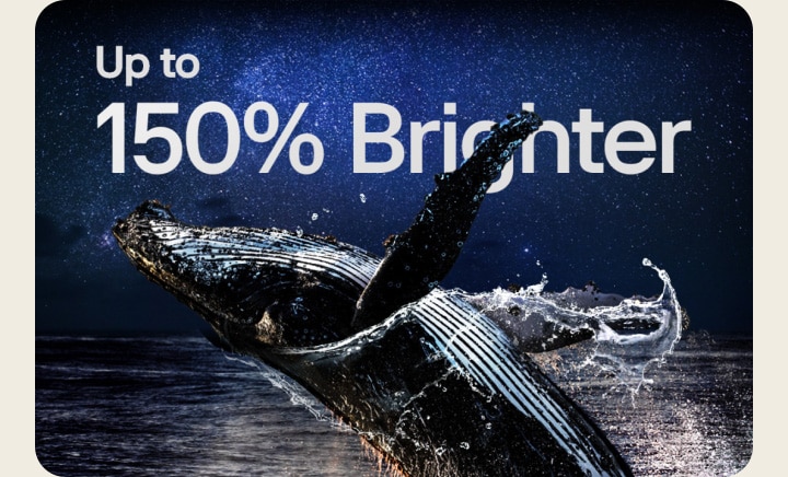 星空の下の暗い海でジャンプする鯨の画像が表示される。その後、「Up to 150% brighter（最大150%鮮やか）」という文字が星空にフェードアウトする。