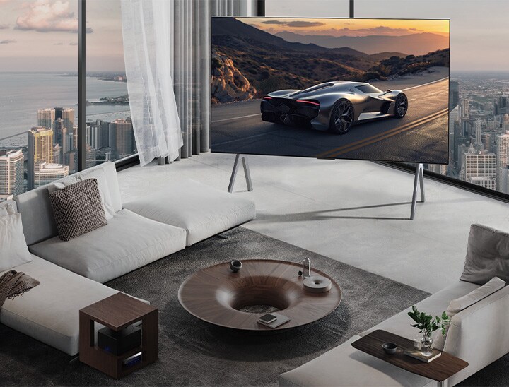 都市の風景を臨むゆったりとしたリビングルーム。LG OLED TVがスタンドに設置されている。超薄型設計であるため、没入感が高い画面。Zero Connect Boxが見えるが、隠されてはいない。