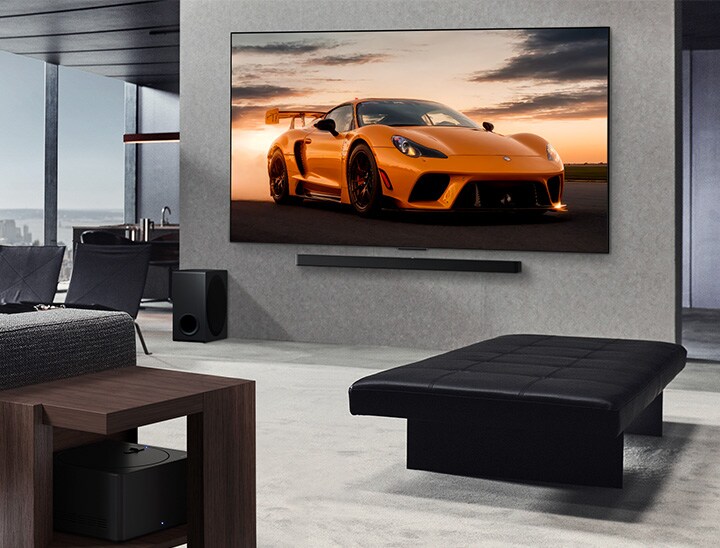 都市の風景を臨むゆったりとしたリビングルーム。LG OLED TVとLG Soundbarが壁に設置されている。TVが超薄型設計であることがわかる。Zero Connect Boxが見えるが、隠されてはいない。