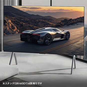 Spacious living room with a view of a cityscape. LG OLED TV is on a stand. The Ultra Slim Design makes the screen feel immersive.  Zero Connect Box is visible, but concealed. 