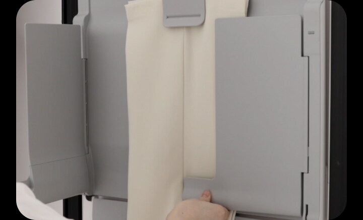 LG StylerでマルチプレートのEZ Fit PantsPress™を使用して、パンツのシワを取り除き折り目を復元している人。