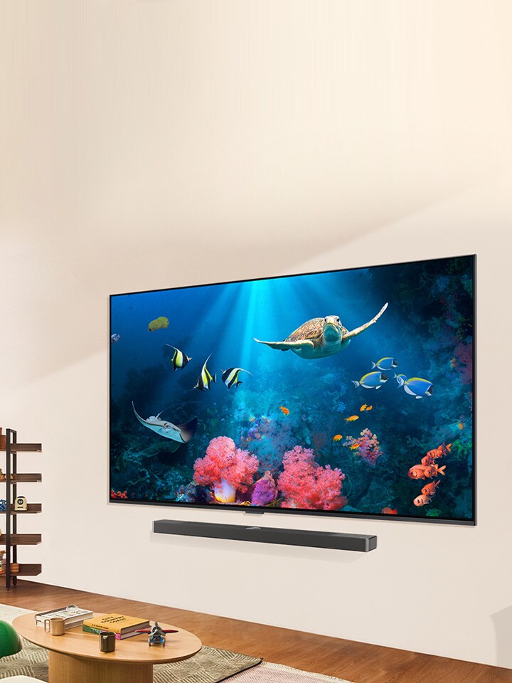Una familia está viendo una brillante escena acuática en una LG QNED TV con una LG Soundbar, en una sala iluminada y natural.