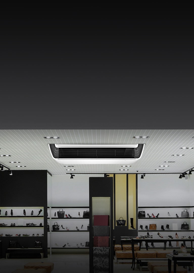 LG Ceiling Suspensed Unit, con un cuerpo blanco con una estructura frontal negra, está montado en el techo adornado con una serie de luces.