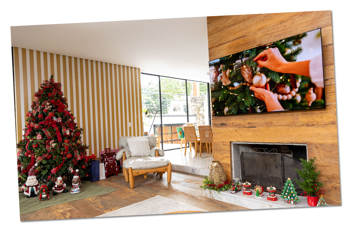 Un árbol de Navidad está decorado en un cálido entorno festivo, mientras el televisor LG OLED muestra un video de decoración navideña en la sala de estar.