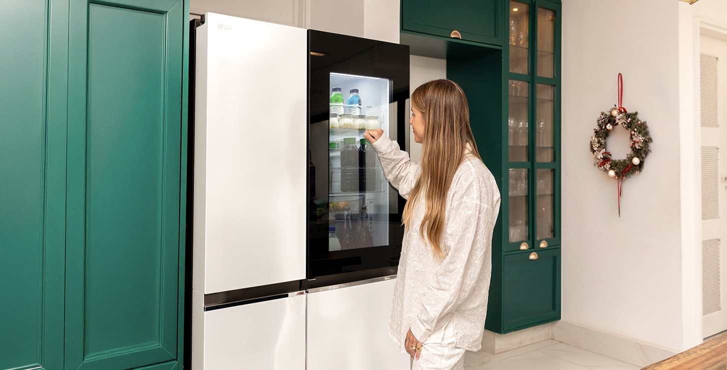 Una mujer está tocando la puerta del refrigerador LG InstaView.