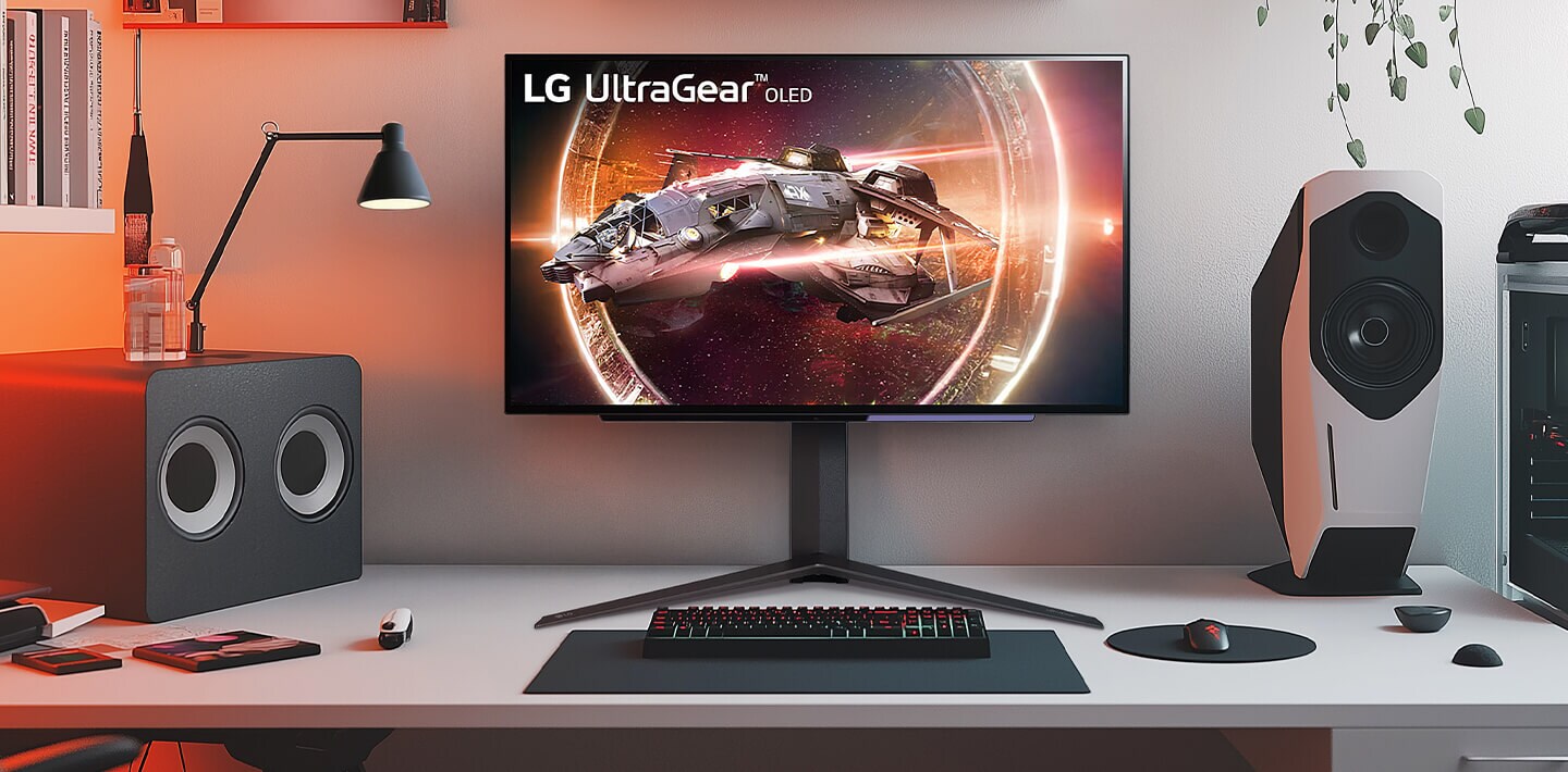 Monitor LG UltraGear mostrando un juego de naves espaciales en una configuración gamer con altavoces y PC.