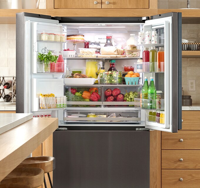 Vista interior totalmente abastecida del refrigerador LG, mostrando estantes organizados con frutas, verduras y bebidas.
