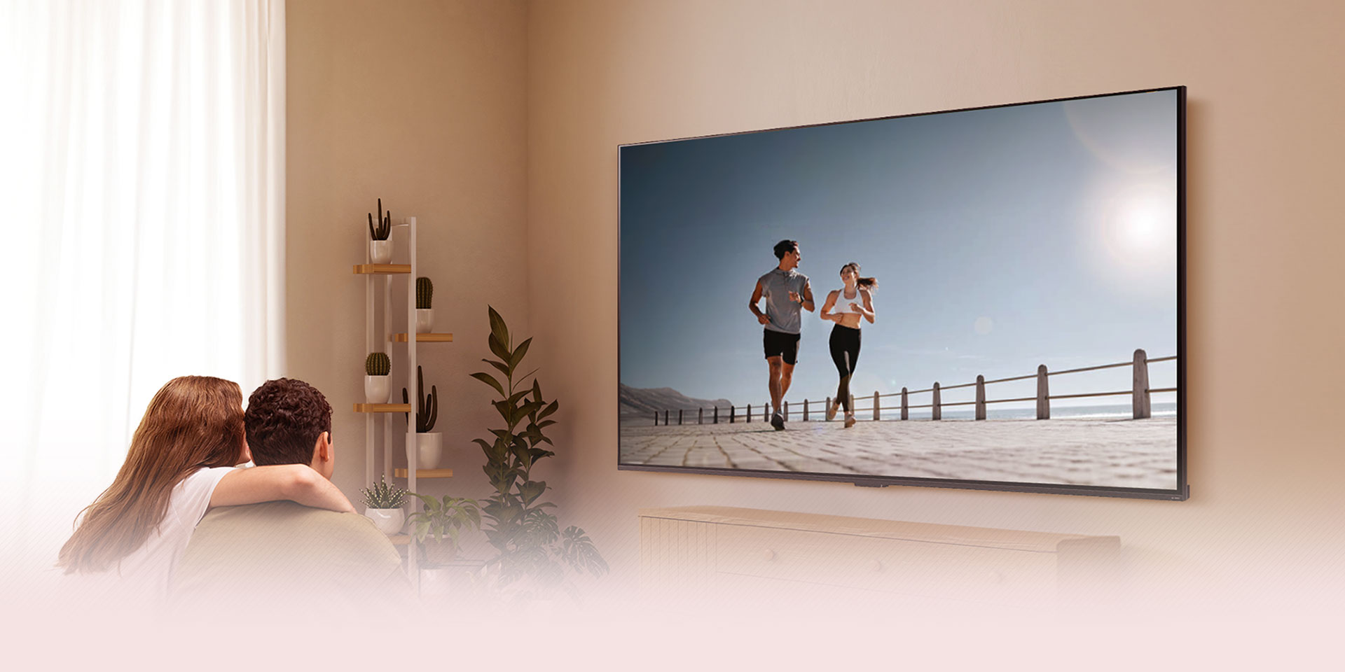 Pareja sentada en el sofá viendo una TV LG con una escena de dos personas corriendo junto al mar.