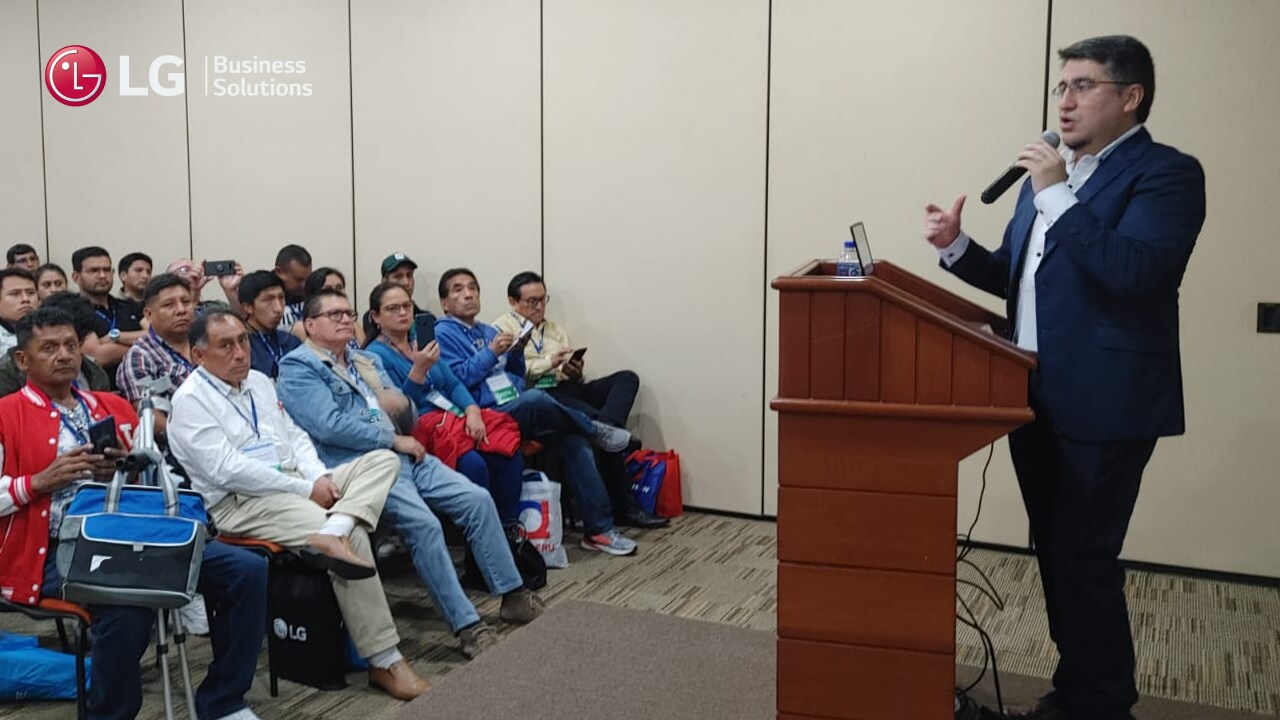 Presentador de LG hablando frente a una audiencia atenta en una sala de conferencias.