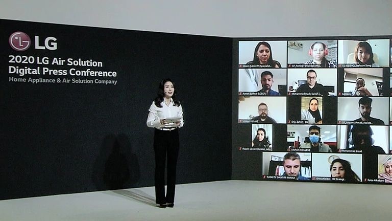 Conferencia de prensa digital de LG Air Solution 2020, con una presentadora en el escenario y varias personas en una videollamada proyectada en la pantalla grande.