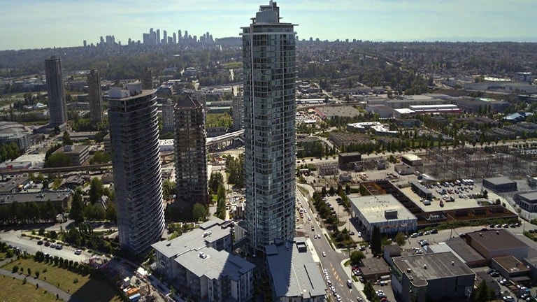 Vista aérea de una ciudad con rascacielos y edificios altos, destacando una torre en el centro rodeada de otras estructuras urbanas.