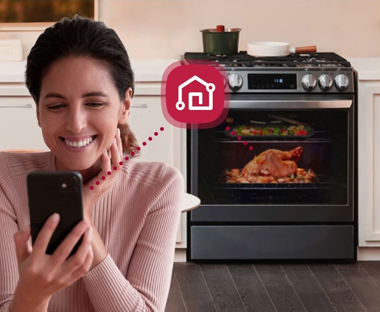 Mujer observa su teléfono y se muestra la conectividad y estado del refrigerador vía la app LG ThinQ.