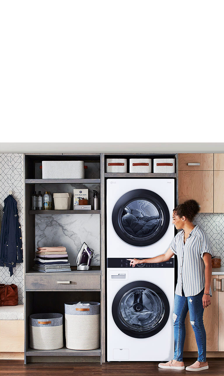 La LG WashTower™ con diseño estilizado maximiza el espacio en una sala de lavado organizada con muebles de almacenamiento.
