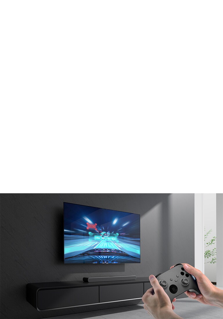 La barra de sonido se coloca en el gabinete y la escena del juego de carreras se muestra en el televisor conectado a la barra de sonido. Una consola de juegos está en la parte inferior derecha de la imagen sostenida con dos manos.
