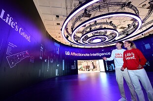 Visitantes observando la pantalla LED de LG, que muestra el eslogan  "Life's Good" y "LG Affectionate Inetelligence"
