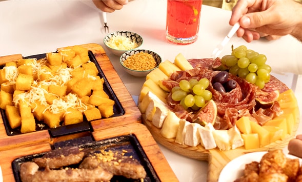 Exhibición de alimentos y bebidas de fiesta como queso, salami y frutas.