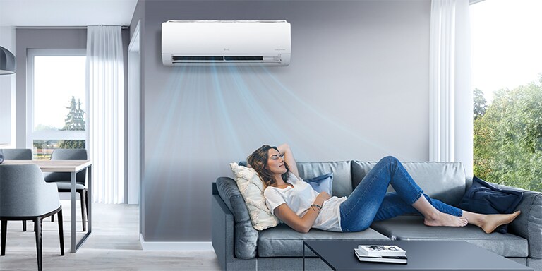 A woman is lying on the sofa, relaxing in the cool air conditioner breeze.