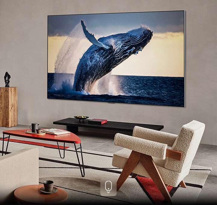 Woonkamer met een tv aan de muur. Op het beeldscherm wordt een hoogwaardige afbeelding getoond van een walvis die uit het water springt.