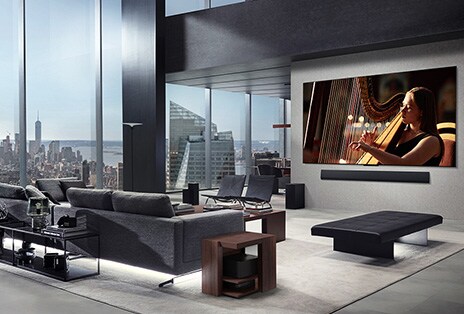 Woonkamer met een LG True Wireless TV en een LG Soundbar die op de wand zijn gemonteerd. De Zero Connect Box is nauwelijks te zien onder een bijzettafeltje bij de bank en het laat zien dat hij gemakkelijk overal geplaatst kan worden. De hele indeling van de woonkamer ziet er netjes en opgeruimd uit.