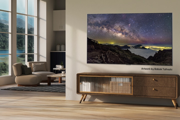 Interieur van een landelijk huis. Een grote wandgemonteerde LG TV heeft een kunstwerk van een prachtig natuurlandschap in beeld. De TV lijkt net een foto die op een muur is gehangen. 