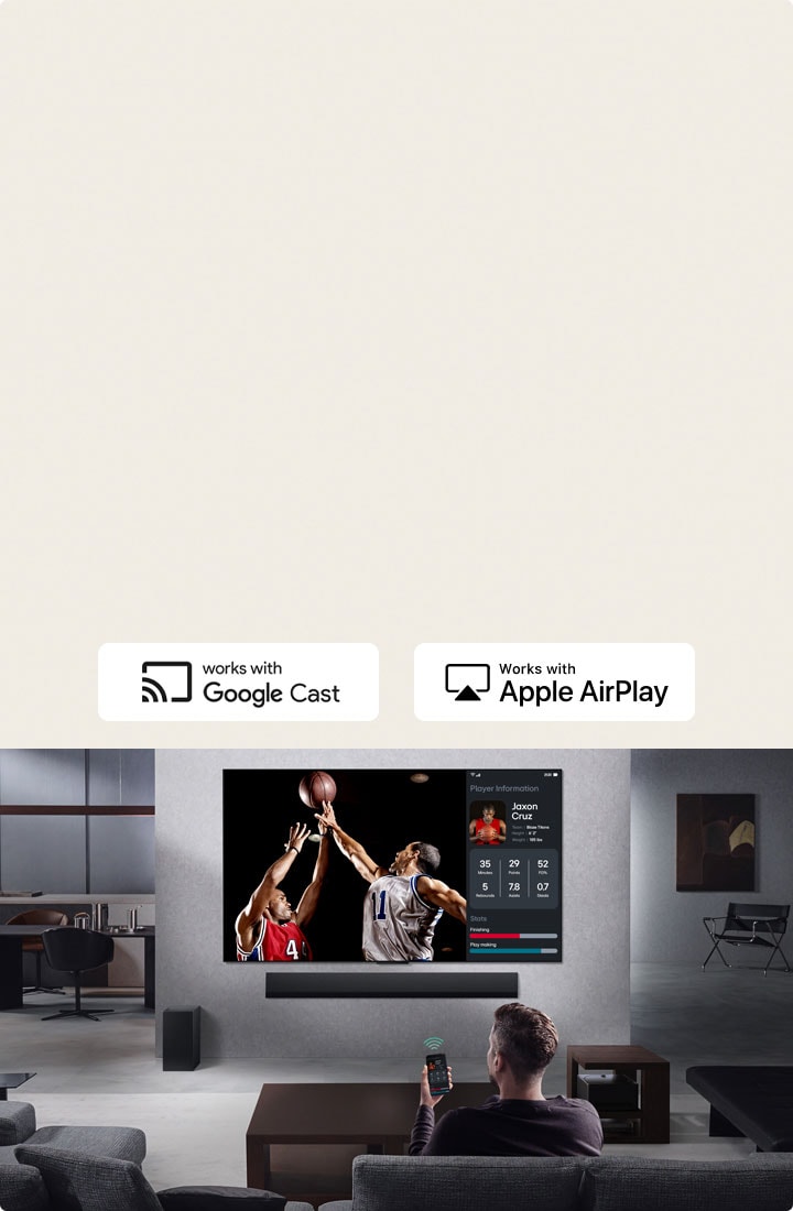 Iemand zit in de woonkamer met een telefoon in de hand. Op de telefoon zien we een pictogram dat aangeeft dat het scherm wordt gespiegeld op de tv. Op de tv is een basketbalwedstrijd te zien en daarnaast het gespiegelde scherm met de statistieken van de spelers. 