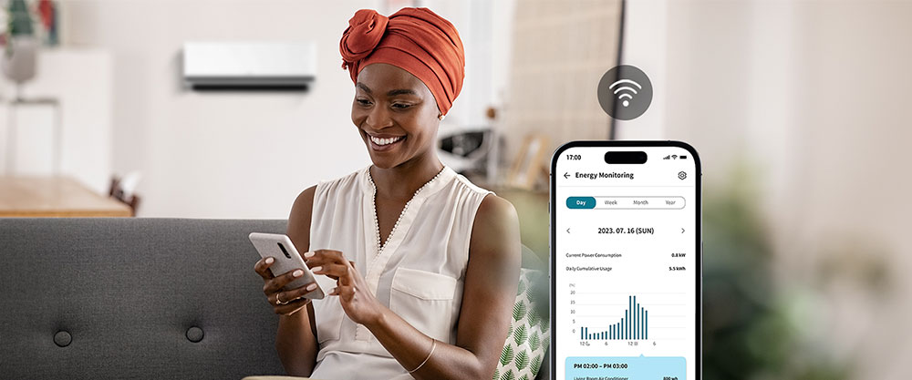 Een vrouw die geniet van de koele wind van de airconditioner controleert het energieverbruik van de airconditioner via het scherm van de ThinQ™-app.