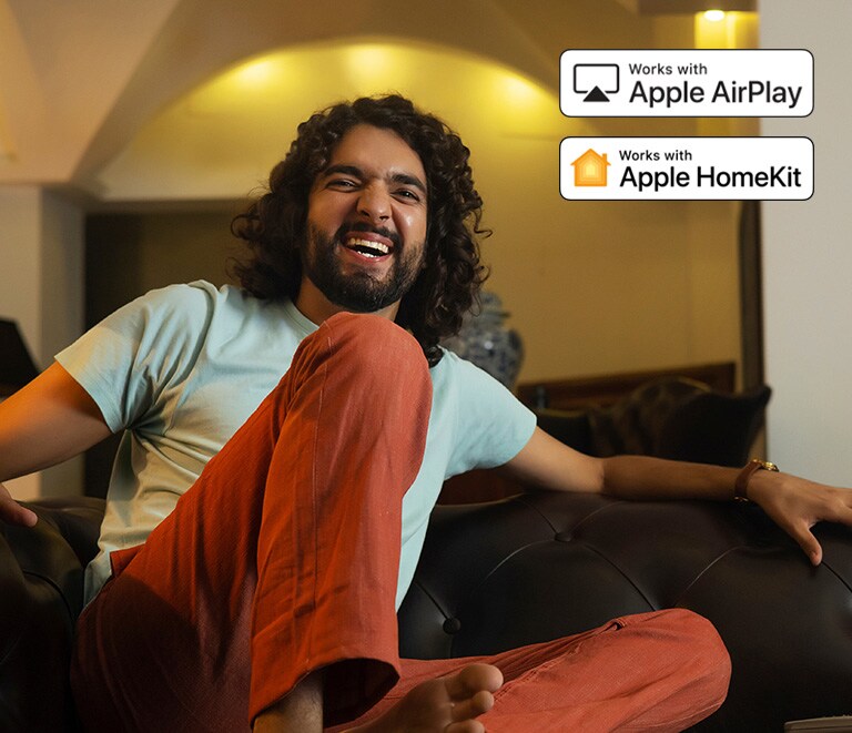 Een man kijkt heel blij naar iets. Er is een Apple AirPlay-logo en een Apple HomeKit-logo in de rechterbovenhoek. 