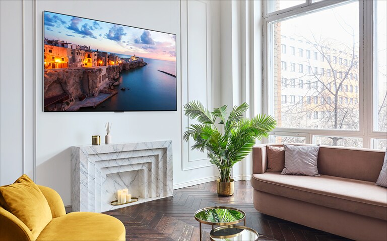 Een scherm met de webOS 23 New Home UX schuift naar rechts, en een landschapsopname verschijnt op het scherm. De zwarte achtergrond wordt een heldere en moderne leefruimte met LG OLED die aan de muur hangt.