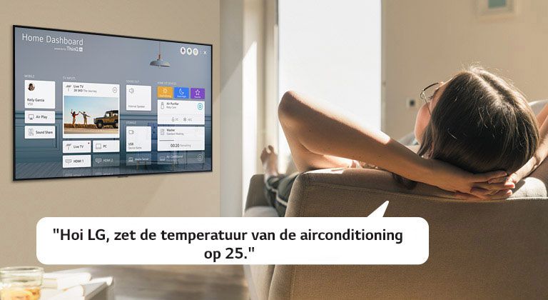 Vrouw liggend op een bank vertelt de tv om de temperatuur te verlagen met het home dashboard op het tv-scherm