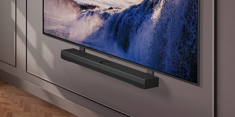 Synergy-beugel met LG QNED TV. Synergy-beugel en LG QNED TV zijn met elkaar verbonden en het beeld gaat naar de onderkant van de tv. LG Soundbar verschijnt terwijl deze op de Synergy-beugel wordt geplaatst. De achtergrond verschijnt met de muur.