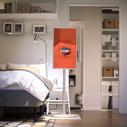 StanbyME staat in de slaapkamer vlak bij een knus bed. Het scherm toont een afbeelding van de cover van een muziekalbum.