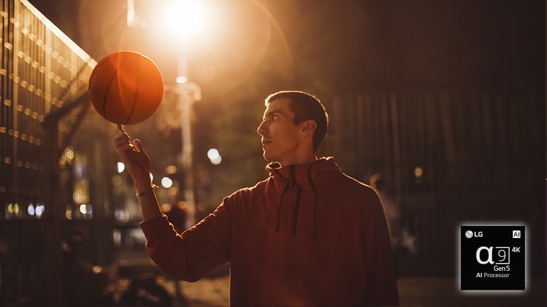 Een man in een basketbalveld bij nacht draait een basketbal op zijn vinger