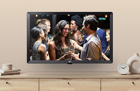 Een tv-monitor met wandmontage hangt boven een kast in de huiskamer en speelt een scène uit een film af.