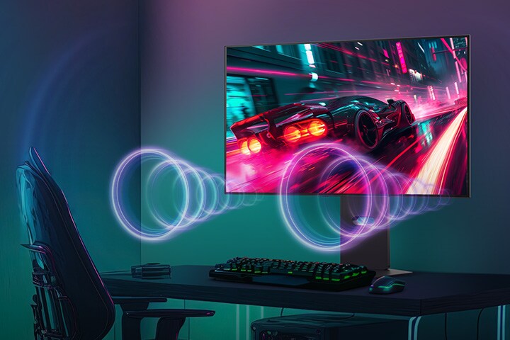 La pantalla del monitor muestra un juego de carreras, mientras que el sonido proviene de los parlantes en la parte inferior del monitor.