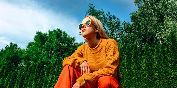 Una mujer agachada afuera en un día soleado frente a los árboles y un cielo azul en el patio, imagen pixelada. El efecto de mapeo tonal y potenciador de la expresión recorre la mujer, haciendo que la zona sea más luminosa. Luego se escanea el fondo, haciéndolo más brillante.