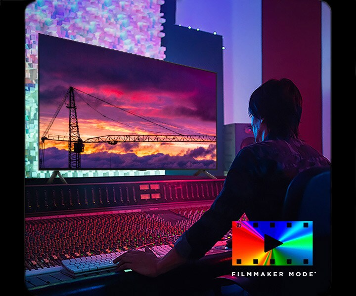 Un hombre en un estudio oscuro de edición mirando un LG TV que muestra el atardecer. En la parte inferior derecha de la imagen se encuentra el logotipo de FILMMAKER Mode.