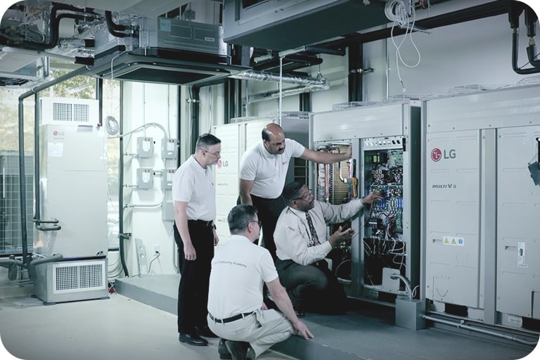 A group of technicians in a mechanical room receiving hands-on training on HVAC equipment.