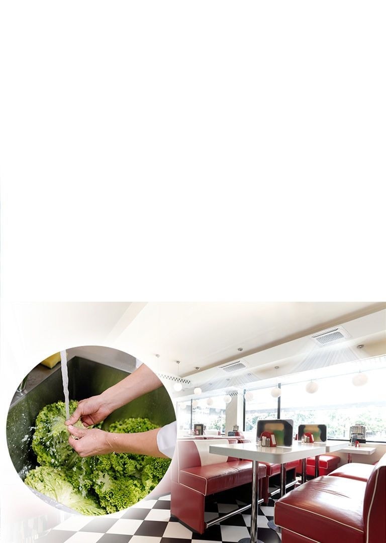 MULTI V S creating cool air stream in a large cafeteria with arrays of tables and sofas. Enlarged image of hands washing lettuce with water in a sink.